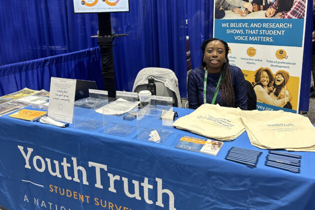 Treva Patton sitting at a YouthTruth emblazoned booth during a conference.