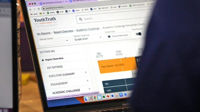 A laptop screen partially obscured by the viewer's shoulder, with a YouthTruth report displayed