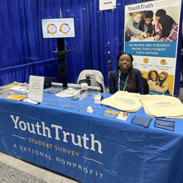 Treva Patton sitting at a YouthTruth emblazoned booth during a conference.