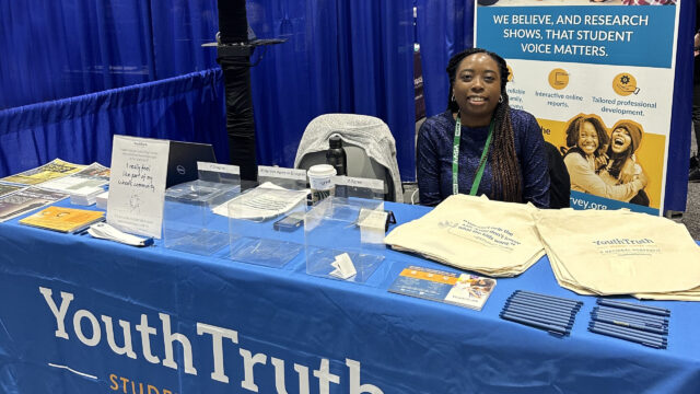 Treva Patton sitting at a YouthTruth emblazoned booth during a conference.