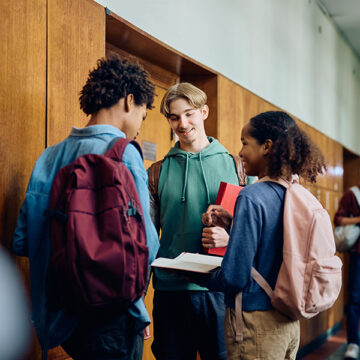 Multiracial group of high school students communicating in hallway.