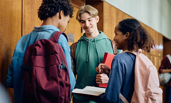 Multiracial group of high school students communicating in hallway.